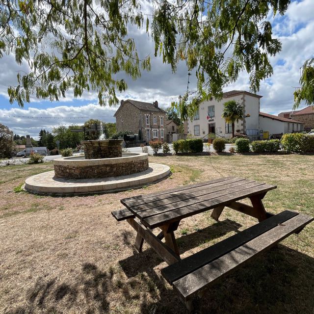 La place du bourg avec sa fontaine en pierre, face à la mairie
